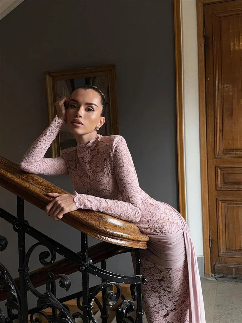 Woman in a pink lace dress sitting on a staircase railing.