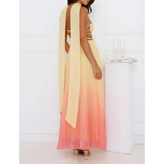 Woman wearing a long, gradient dress with a cape against a white background