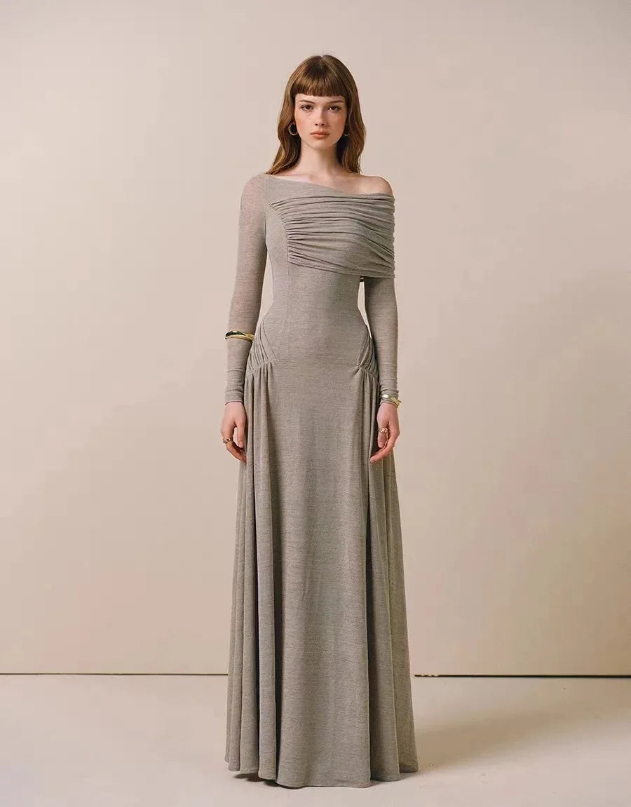 Woman wearing a long, off-shoulder dress with long sleeves against a plain background