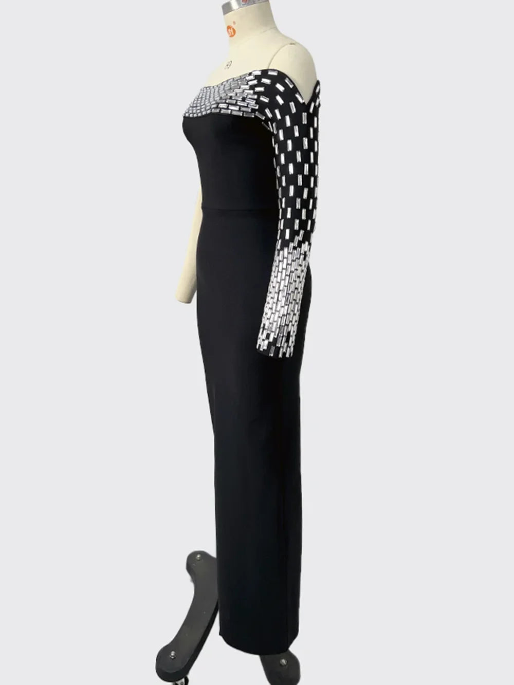 Black evening gown with silver embellishments on a mannequin against a white background