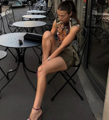 Woman sitting on a chair outside a cafe with tables and chairs around her.