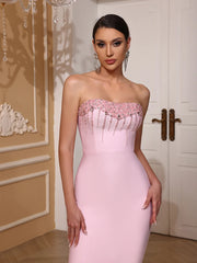 Woman wearing a pink strapless gown with floral details in an elegant indoor setting.