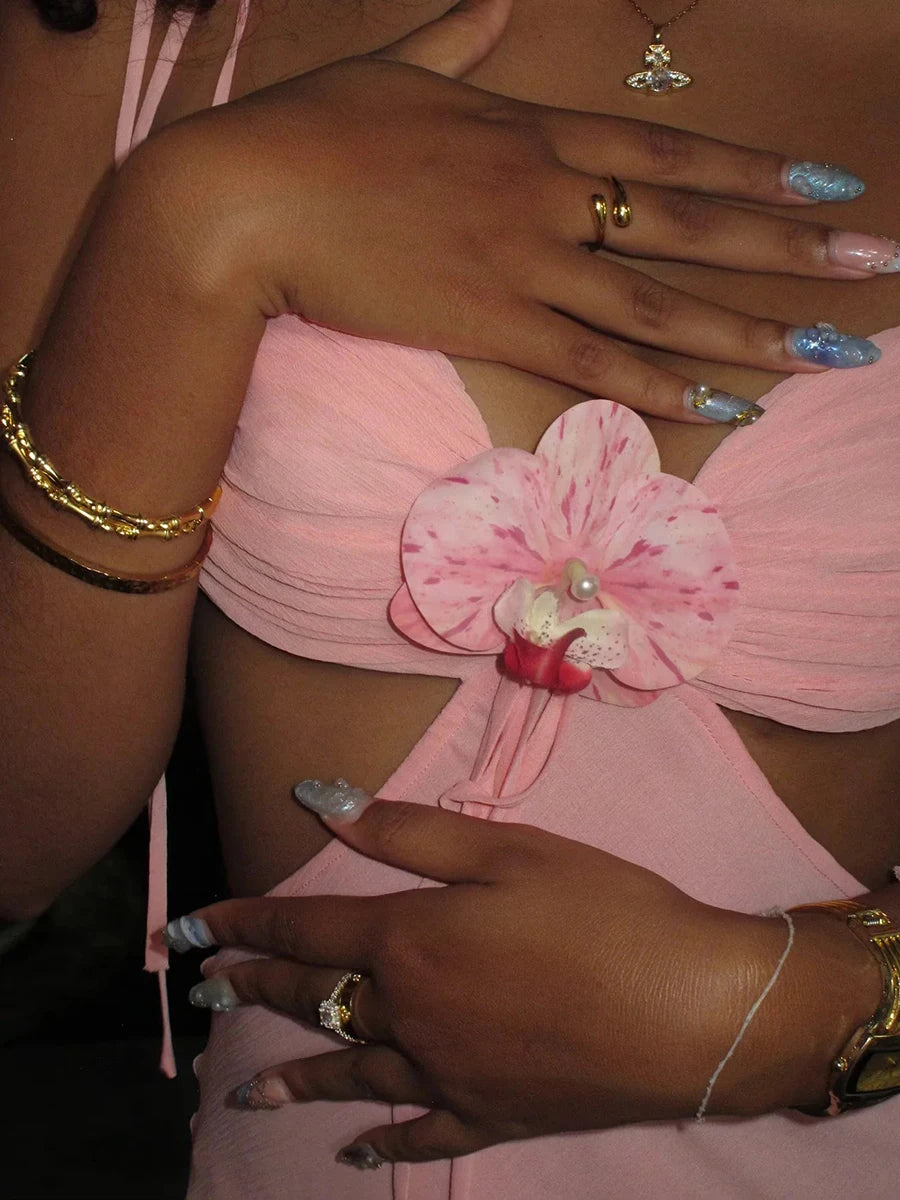 Close-up of a person wearing a pink strapless top with floral details.
