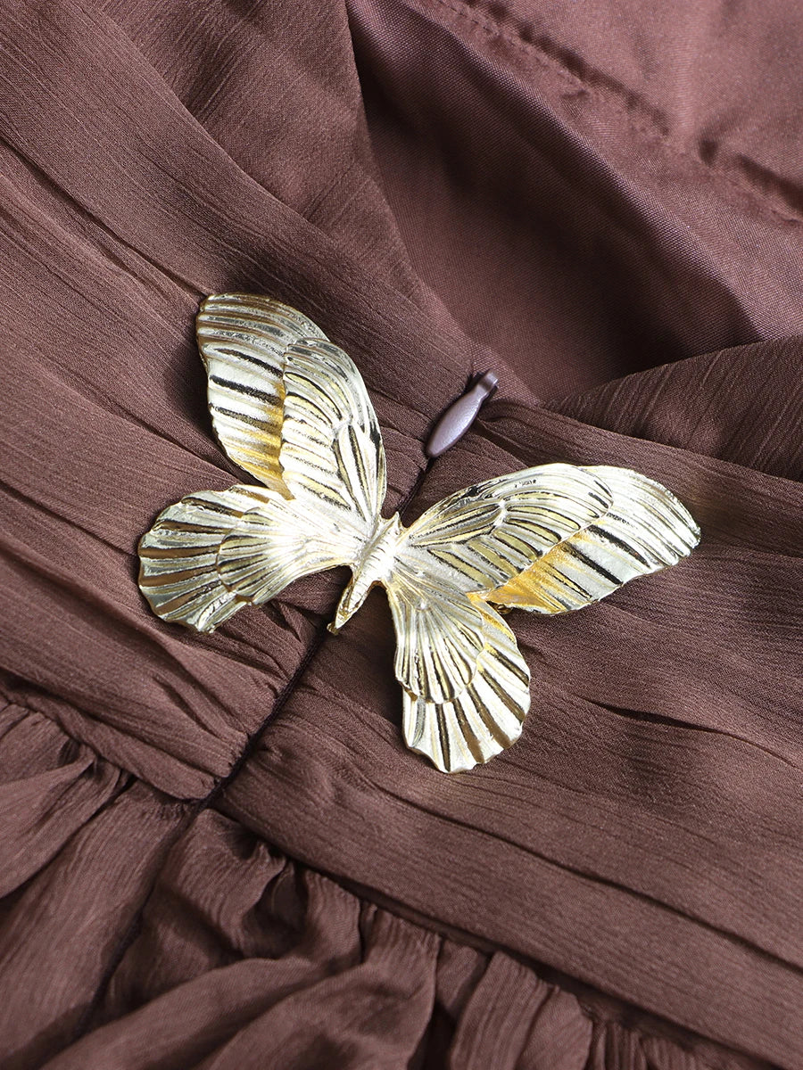 Gold butterfly brooch on a brown fabric background