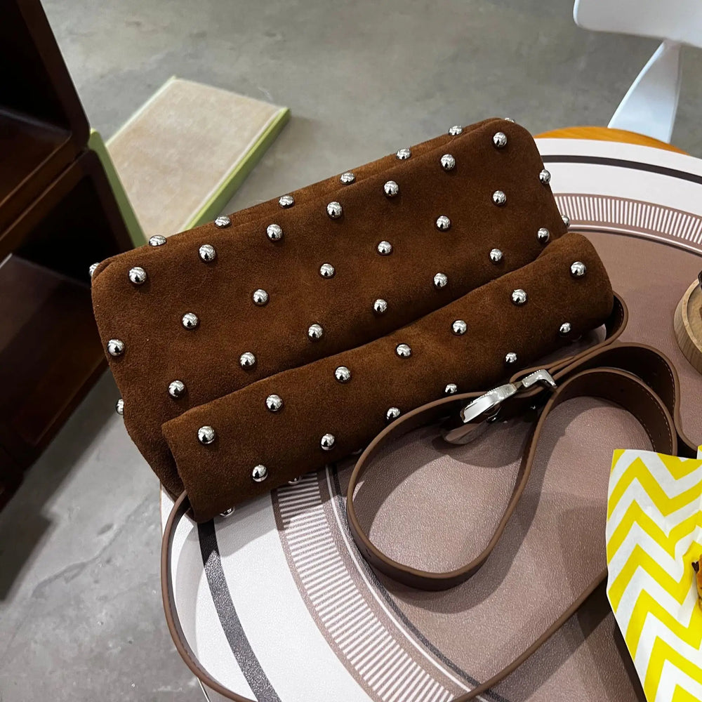 Brown studded handbag on a round surface with a blurred background