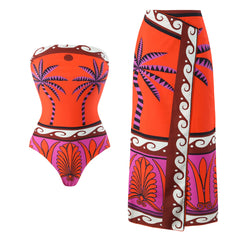 Orange strapless one-piece swimsuit with palm tree print and matching printed sarong.
