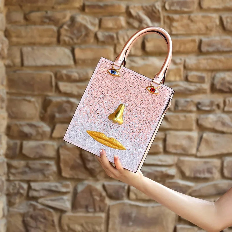 Pink embellished sculptural face bag with gold-tone nose and lips, and jewel-toned eye accents.