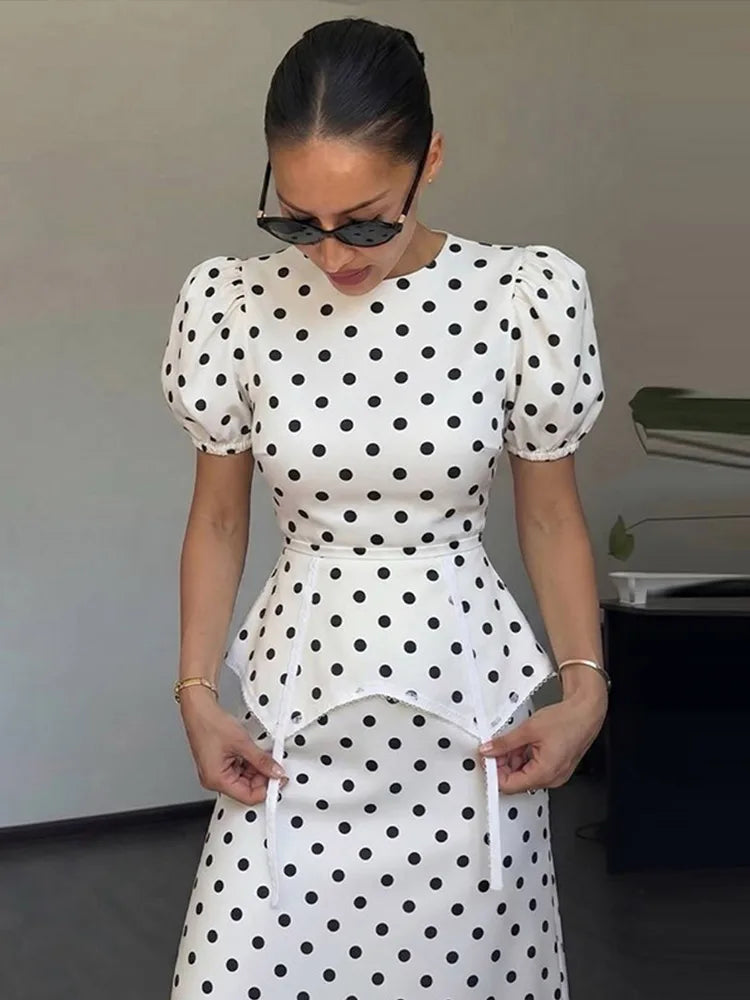 Model adjusting white polka dot peplum dress