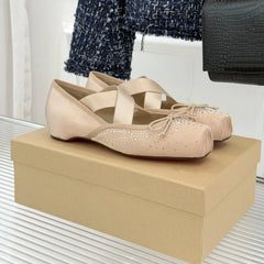Pair of beige shoes with rhinestone details on a beige box.