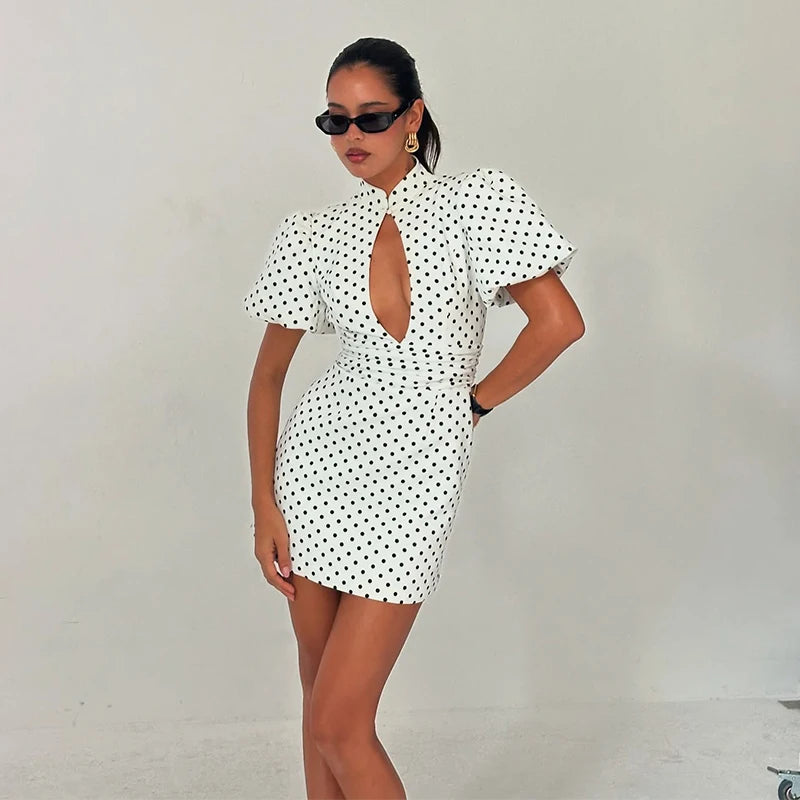 Woman wearing a white dress with black polka dots against a plain background