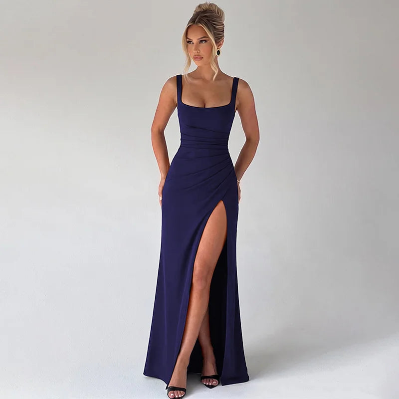 Woman wearing a long navy blue dress with a high slit on a white background