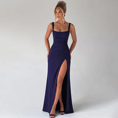 Woman wearing a long navy blue dress with a high slit on a white background