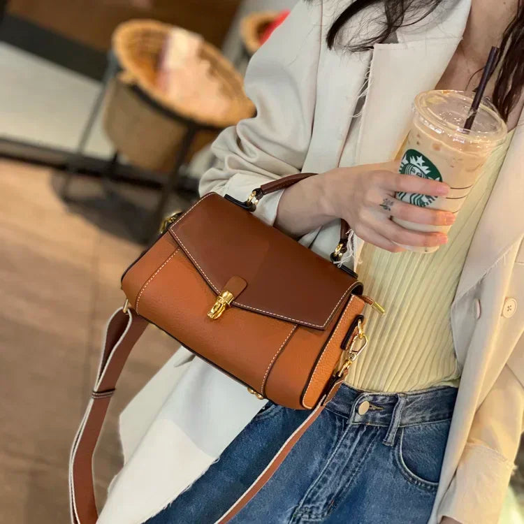 Person holding a brown handbag and a Starbucks drink in an indoor setting