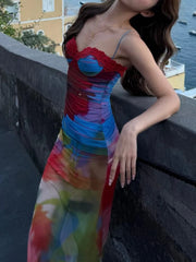 Woman wearing a colorful dress leaning against a railing with a waterfront background
