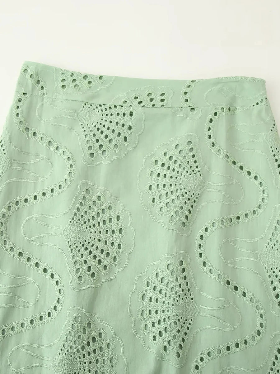 Close-up of a light green skirt with eyelet detailing on a white background