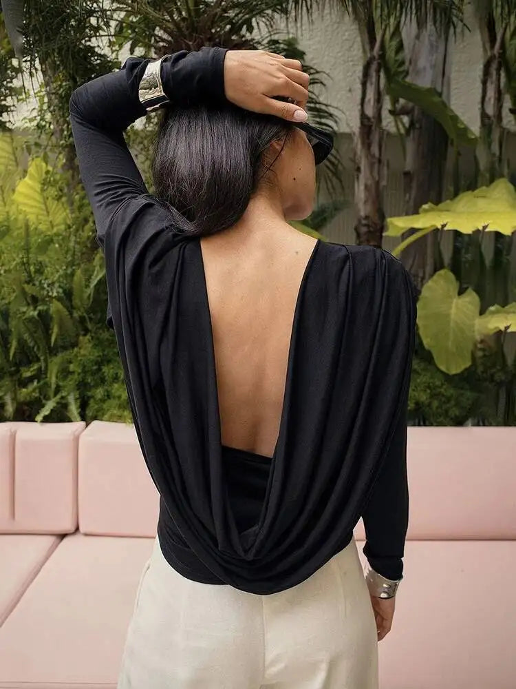 Person wearing a black open-back top with a blurred background