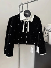 Black jacket with white polka dots and collar on a hanger against a gray background