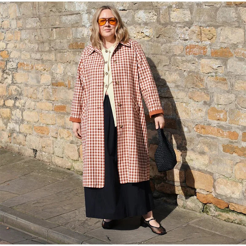 Woman wearing a checkered coat against a stone wall