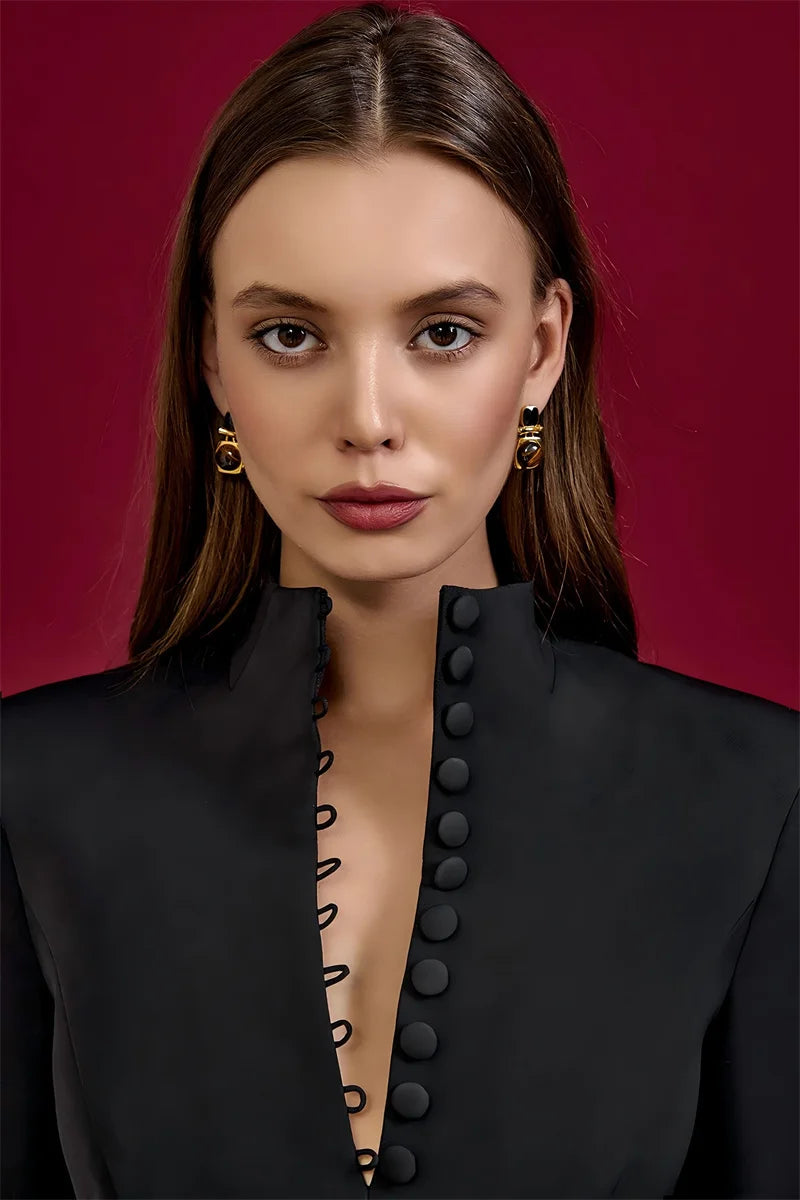 Woman wearing a black outfit with button details against a red background