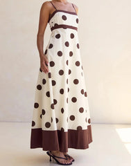 Woman wearing a polka dot dress with brown and white colors on a plain background