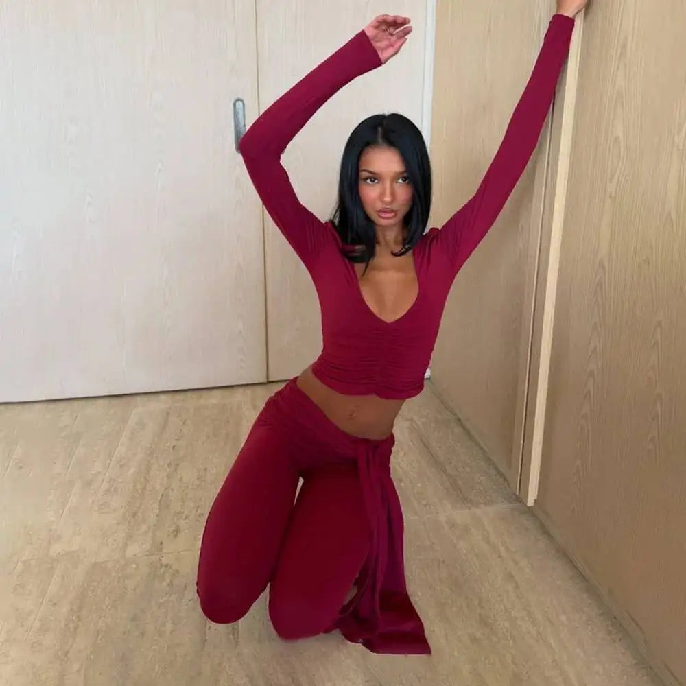 Model in a ruched v-neck long sleeve crop top and bandage capri pants set posing on the floor.