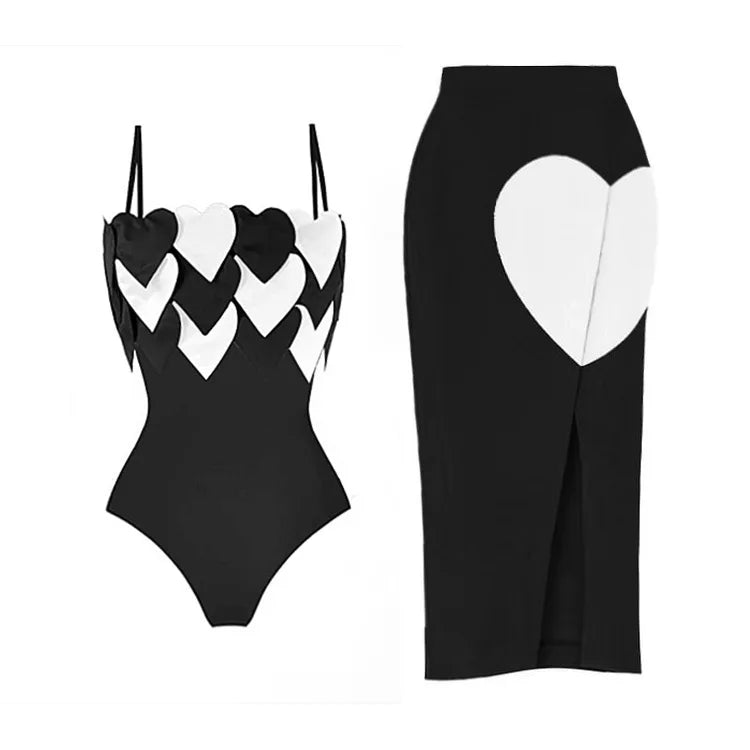 Black one-piece swimsuit with white heart accents and a black beach skirt with a white heart detail.