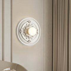 A round Art Deco wall sconce with a milk white glass shade, casting a warm glow B