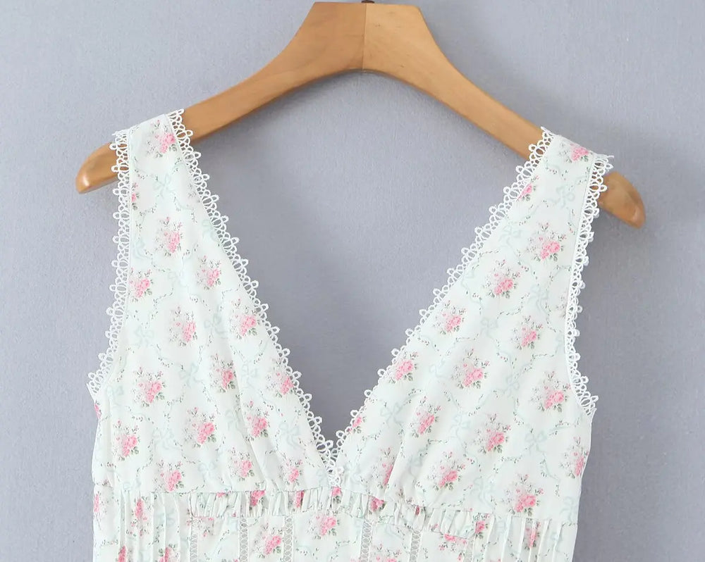 White lace top with pink floral patterns on a wooden hanger against a gray background