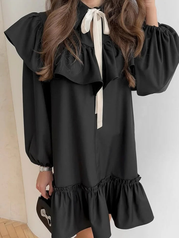 Close-up of the ruffled collar and bow tie on a black mini dress