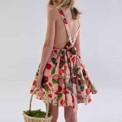 Woman wearing a pink dress with strawberry pattern holding a basket on a white background