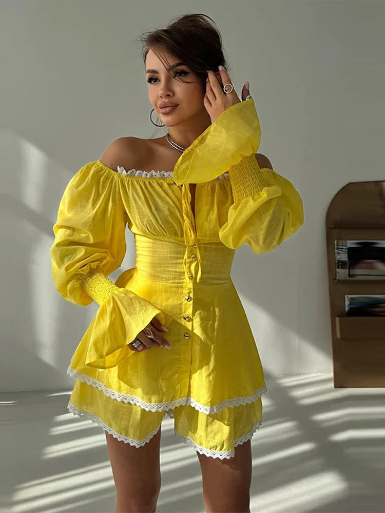 Woman wearing a yellow off-shoulder dress with puffed sleeves in a softly lit room.