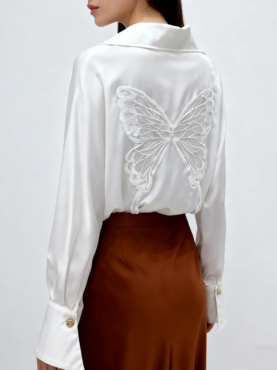 White blouse with butterfly design on the back worn by a person against a white background
