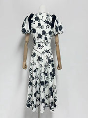 White dress with black floral pattern on a mannequin against a white background