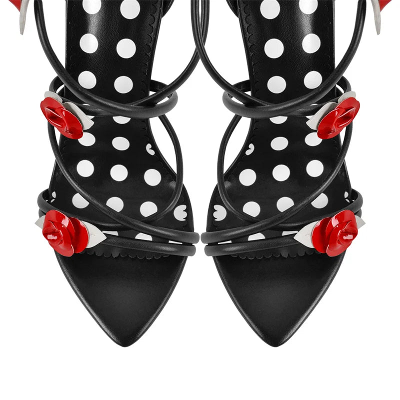 Close-up of the toe area of black lace-up stiletto heeled sandals with rose and polka dot details.