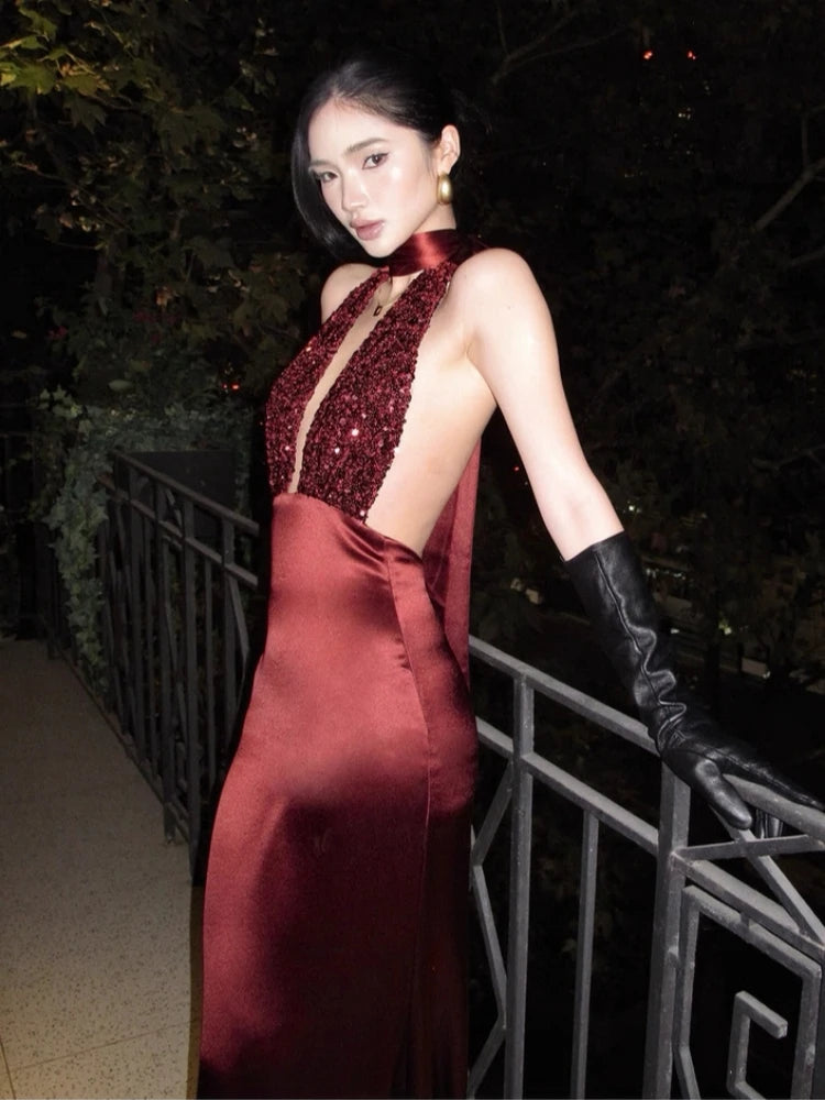 Woman in a red evening gown with a deep neckline and black gloves standing outdoors at night.