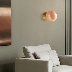 The Golden Atelier Modern Pink Glass Wall Sconce illuminating a stylish living room with a warm, inviting glow. D