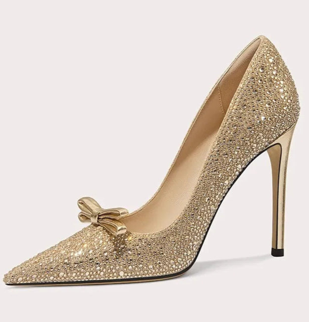 Gold high-heeled shoe with embellishments on a white background