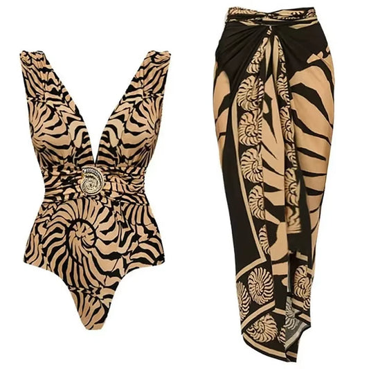 Tan and black animal print textured one-piece swimsuit with gold-tone embellishment and a matching tan and black wrap skirt with a seashell-inspired print.