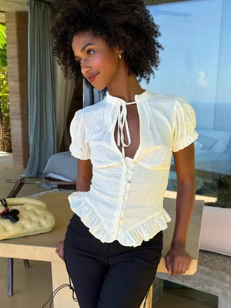 Woman wearing a white smocked peplum blouse with tie neckline
