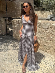 Woman in a black and white checkered dress standing outdoors near stone walls.
