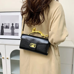 Woman wearing a black embossed top handle bag