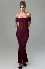 Woman wearing a burgundy off-shoulder lace dress on a gray background