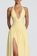 Yellow halter neck dress with a deep neckline and slit on a plain background