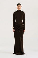 Woman wearing a long black dress with a high neckline on a white background