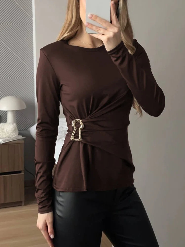 Model wearing brown ruched long sleeve top with metal ring detail