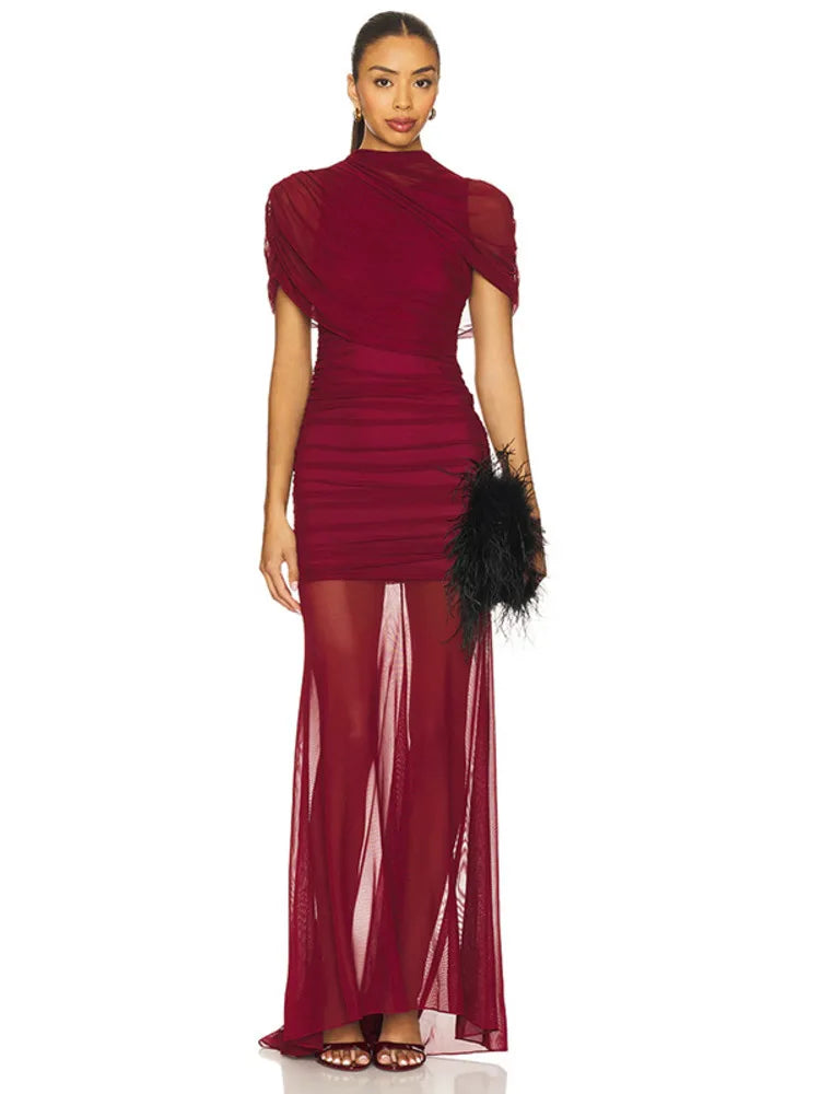 Woman wearing a burgundy evening gown with sheer overlay on a white background