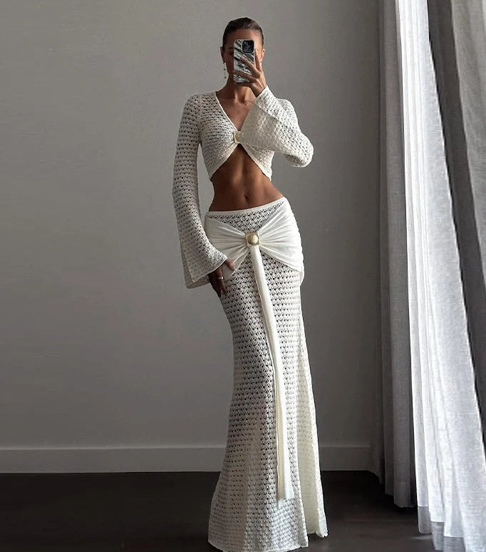 Person wearing a white textured outfit standing in a room with gray walls and curtains.