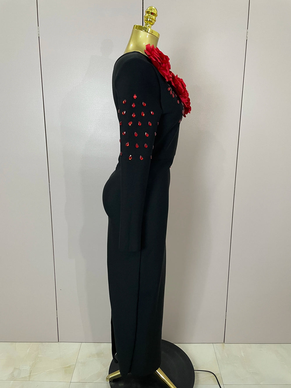 Black outfit with red embellishments on a mannequin against a white wall.