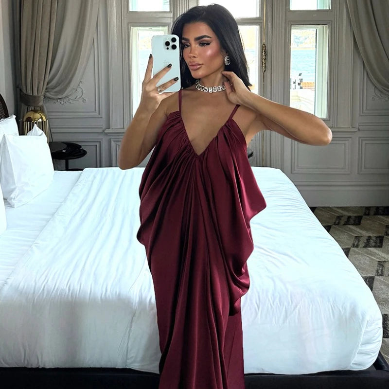 Woman in a burgundy dress taking a mirror selfie in a bedroom.