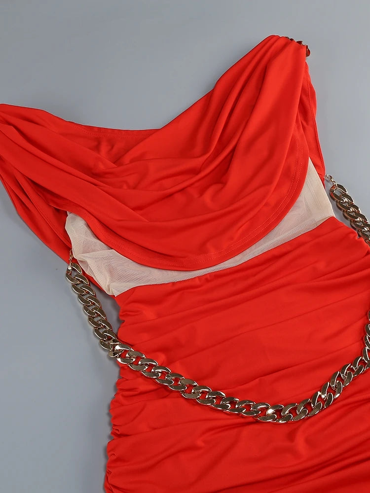Red fabric with a gold chain draped over it on a gray background